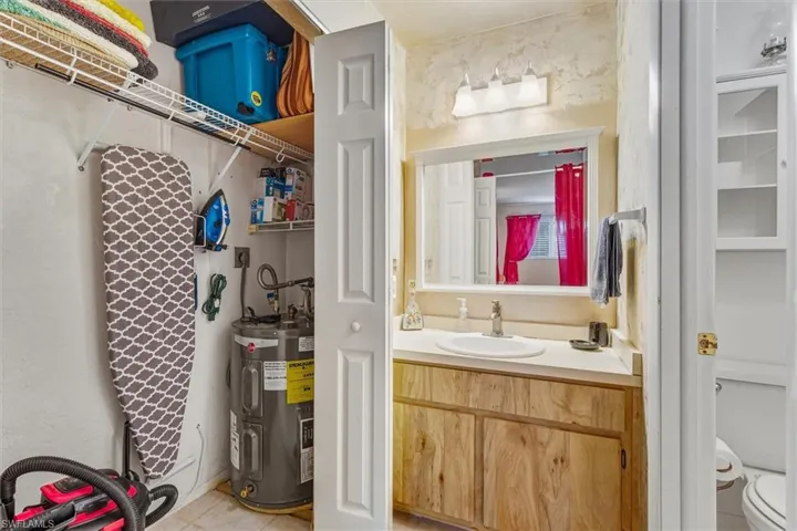 Bathroom featuring vanity, electric water heater, and light tile patterned flooring