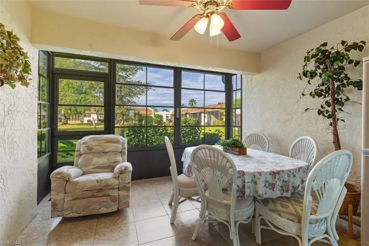Sunroom / solarium with a textured wall, a ceiling fan, outdoor dining space, and tile patterned floors