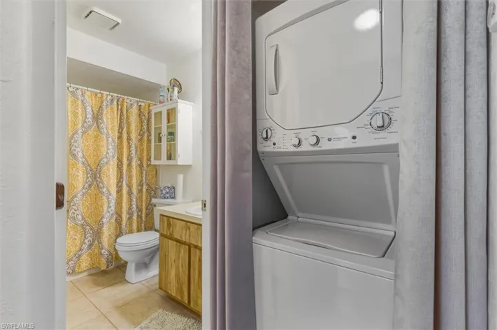 Laundry area with light tile patterned floors and stacked washer / drying machine