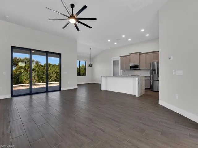 Unfurnished living room featuring a ceiling fan, dark wood-type flooring, lofted ceiling, and recessed lighting