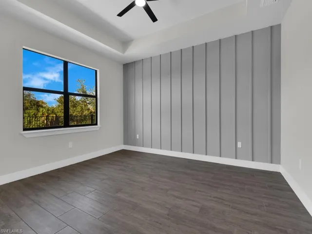 Unfurnished room with dark wood-type flooring, a raised ceiling, and ceiling fan