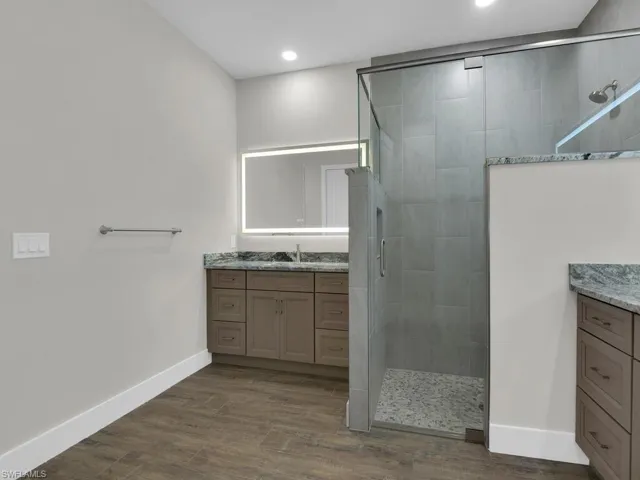 Bathroom with a shower stall, dark wood finished floors, and vanity