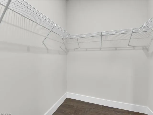 Walk in closet with dark wood finished floors