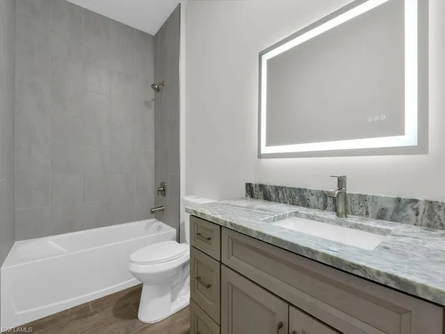 Bathroom featuring vanity, washtub / shower combination, and dark wood-type flooring