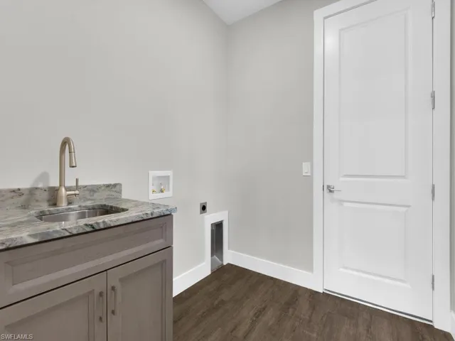 Laundry room featuring dark wood-style flooring, electric dryer hookup, hookup for a washing machine, and cabinet space
