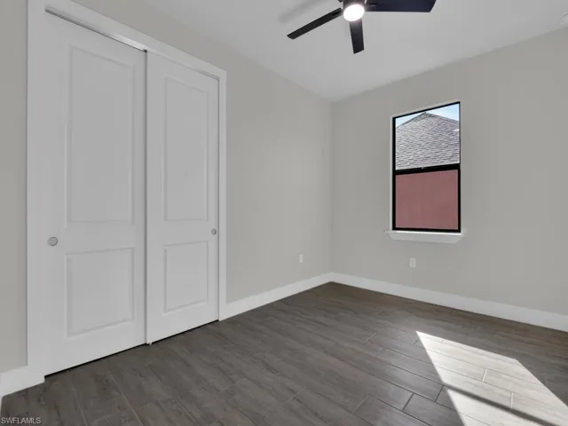 Unfurnished bedroom with dark wood finished floors, a ceiling fan, and a closet