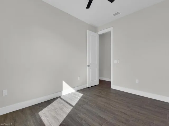 Empty room with dark wood-type flooring and a ceiling fan