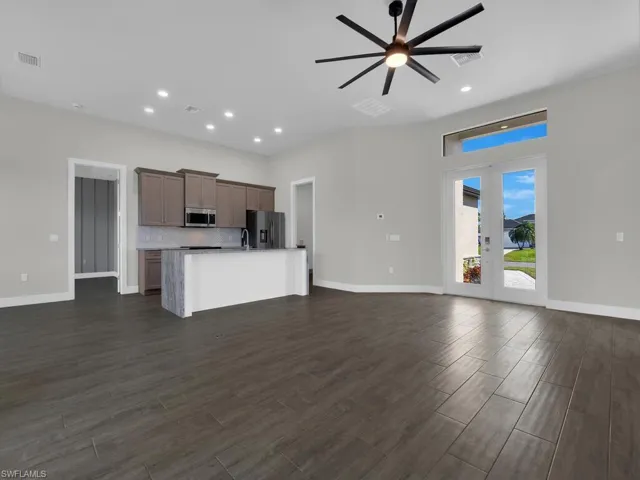 Kitchen with open floor plan, a center island with sink, wood tiled floors, stainless steel appliances, and french doors