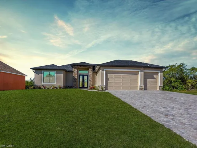 Prairie-style house featuring stone siding, a front lawn, an attached garage, stucco siding, and decorative driveway