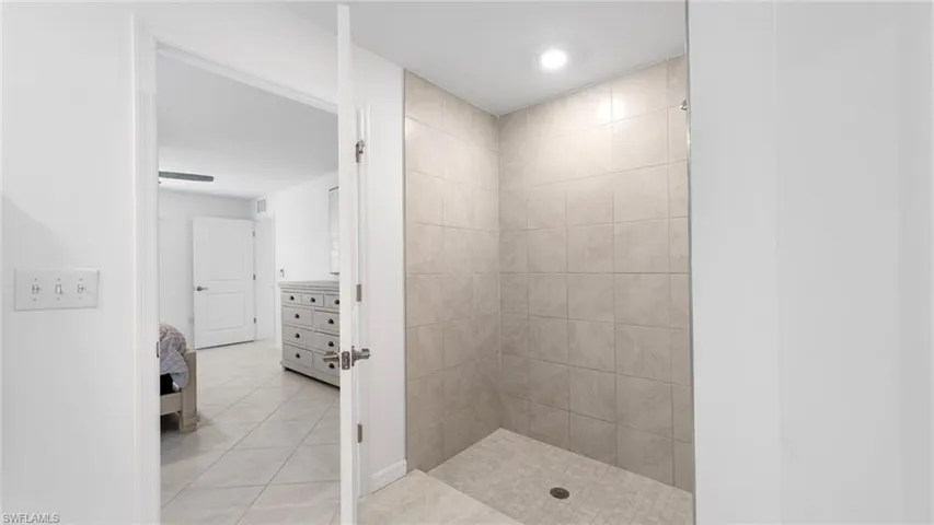 Ensuite bathroom featuring a stall shower and light tile patterned floors