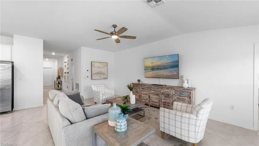 Living area featuring light tile patterned floors, a ceiling fan, and lofted ceiling