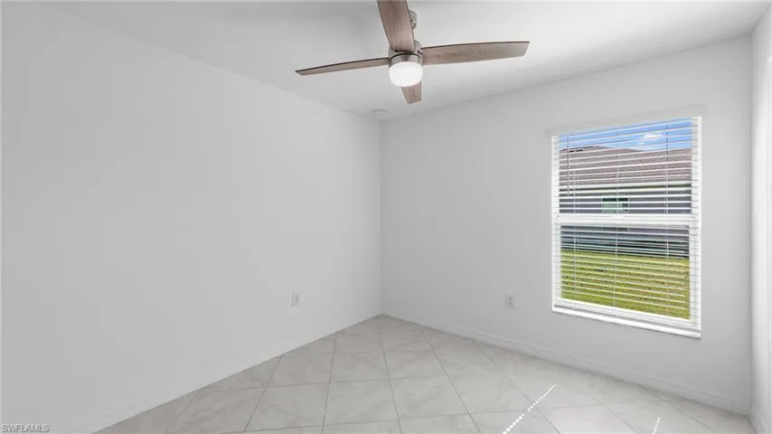 Empty room featuring light tile patterned floors and a ceiling fan