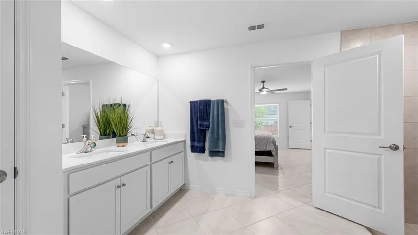 Ensuite bathroom with vanity, light tile patterned flooring, ceiling fan, and recessed lighting