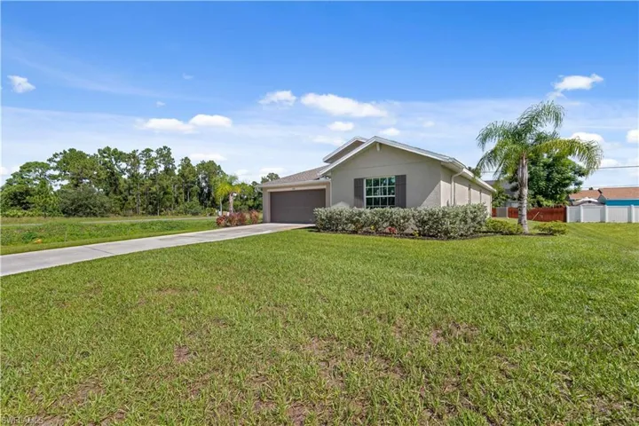 Ranch-style home with concrete driveway, a garage, a front yard, and stucco siding