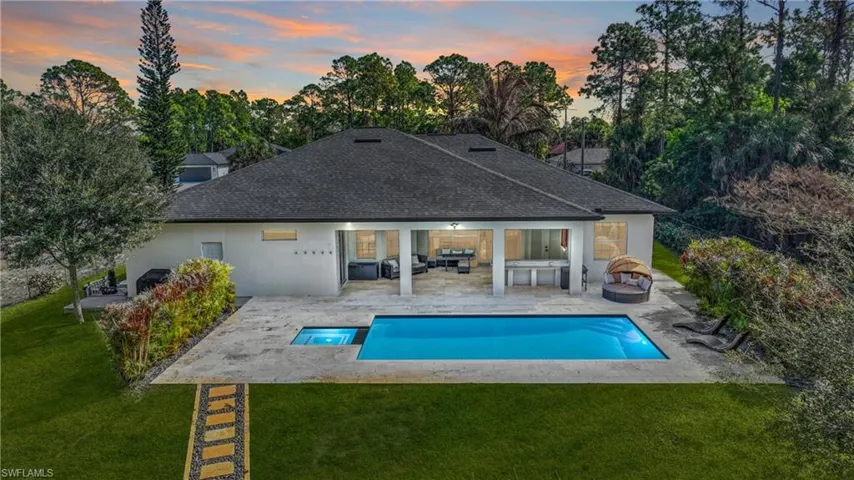 Back of property featuring a yard, a patio, an outdoor pool, and a shingled roof