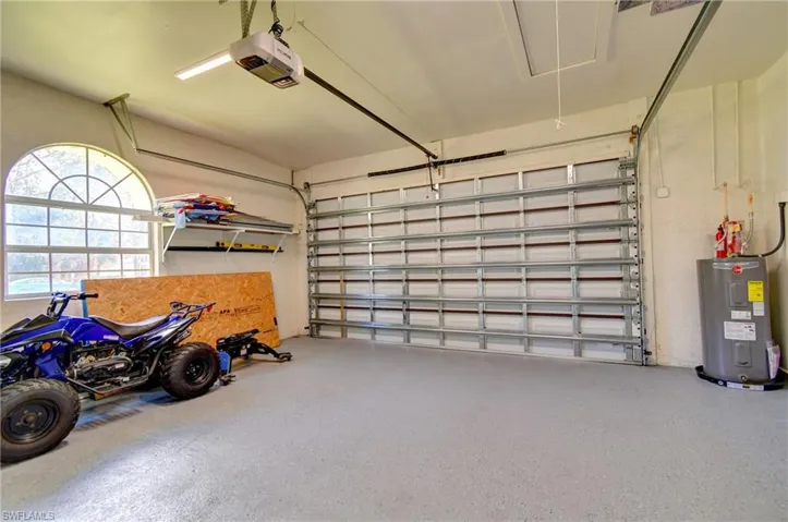 Garage featuring electric water heater and a garage door opener