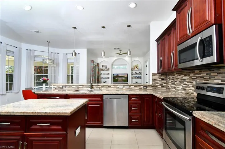 Kitchen featuring bold wood finish cabinetry, stainless steel appliances, and decorative light fixtures