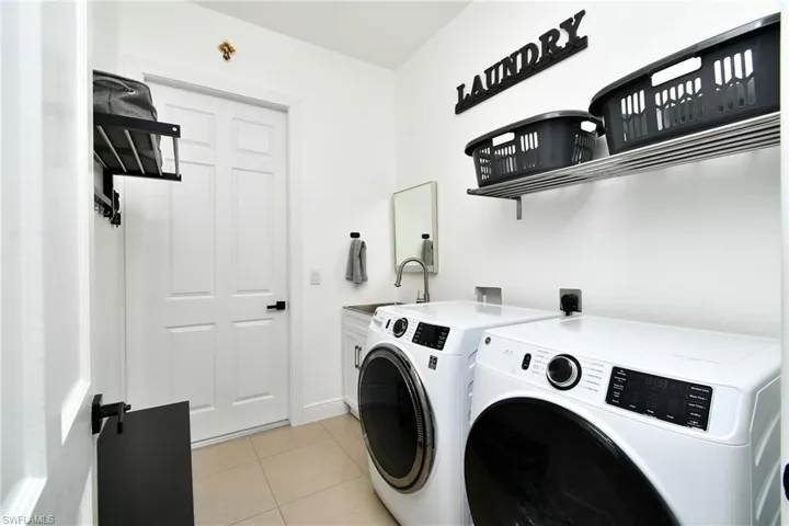 Laundry room featuring separate washer and dryer, light tile patterned floors, and cabinet space