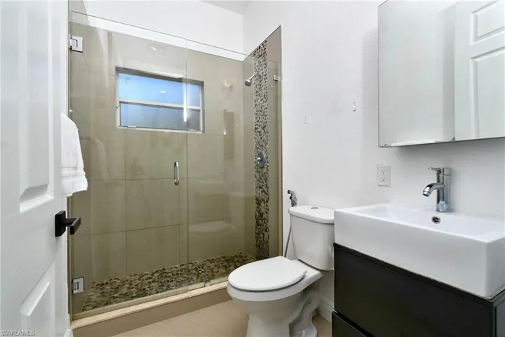 Full bathroom featuring a stall shower, vanity, and a textured wall
