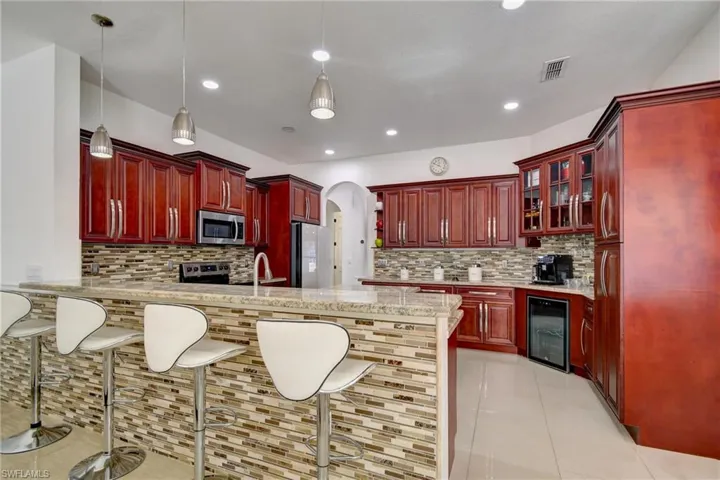Kitchen featuring bold wood finish cabinets, a peninsula, a kitchen breakfast bar, and arched walkways