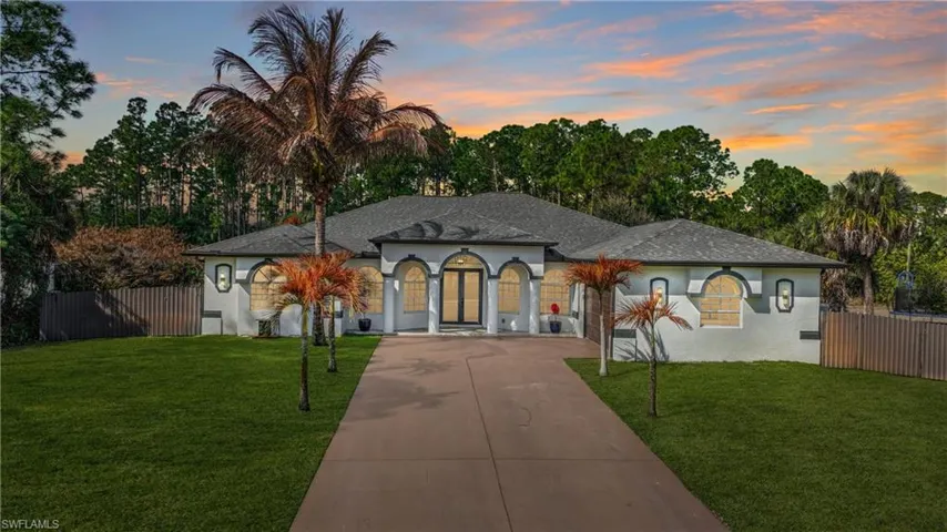 Mediterranean / spanish-style house with driveway, stucco siding, roof with shingles, and view of wooded area
