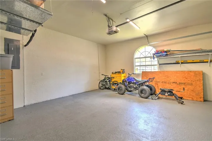 Garage featuring electric panel, a textured wall, and a garage door opener