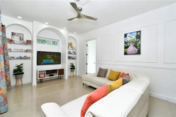 Living area with a ceiling fan, light tile patterned floors, a decorative wall, recessed lighting, and built in shelves