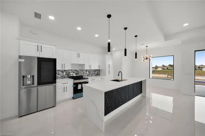 Kitchen featuring appliances with stainless steel finishes, white cabinetry, tasteful backsplash, light stone countertops, and recessed lighting