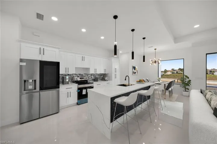 Kitchen featuring appliances with stainless steel finishes, backsplash, a chandelier, white cabinetry, and recessed lighting