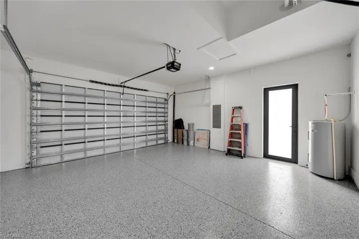 Garage featuring electric water heater and electric panel