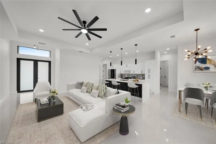 Living area with a tray ceiling, a chandelier, recessed lighting, light tile patterned floors, and a ceiling fan