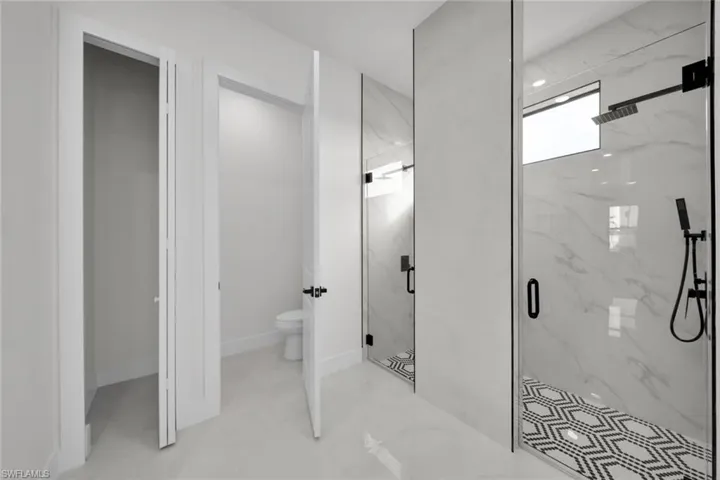 Full bathroom featuring toilet and a marble finish shower