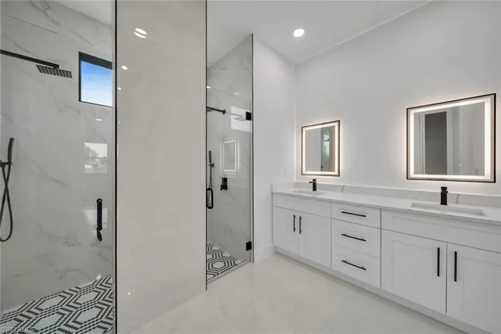 Bathroom with a marble finish shower, double vanity, and recessed lighting
