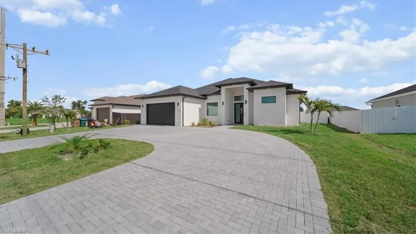 Prairie-style house with a garage, decorative driveway, and stucco siding