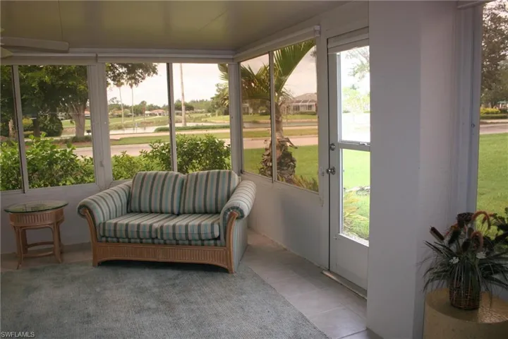 Screened enclosure featuring a ceiling fan, multiple windows, and a glass-paneled door