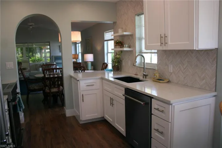 Kitchen featuring white cabinetry, light countertops, an undermount sink, and a herringbone tile backsplash