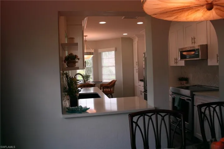 White shaker cabinetry, built-in microwave, stainless steel range, white countertop, and patterned backsplash