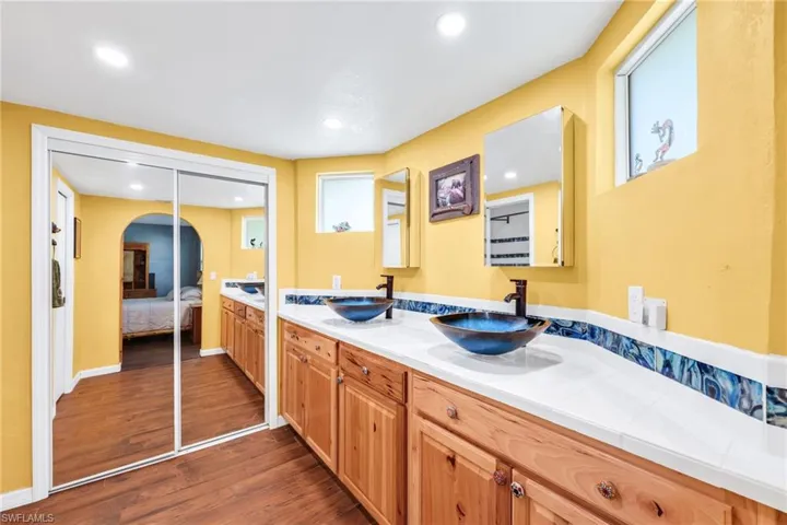 Full bath with double vanity, dark wood-style flooring, ensuite bath, and recessed lighting