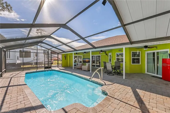 Swimming pool featuring a sunroom, a patio area, and glass enclosure