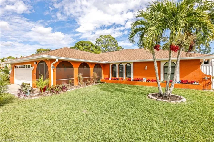 Back of property featuring a lawn, stucco siding, and a garage