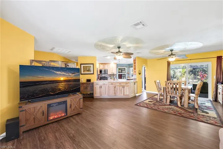Dining room with dark wood-style flooring, a glass covered fireplace, and a ceiling fan