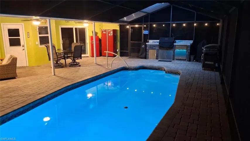 Swimming pool featuring a patio area, a sunroom, area for grilling, and glass enclosure