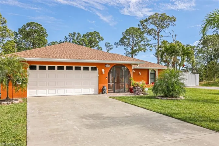 View of front facade with concrete driveway, roof with shingles, a front yard, and stucco siding