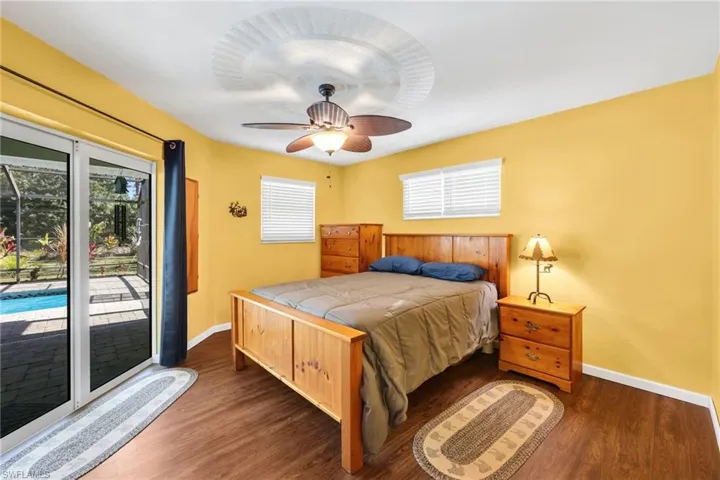 Bedroom featuring access to exterior, multiple windows, dark wood-type flooring, and ceiling fan