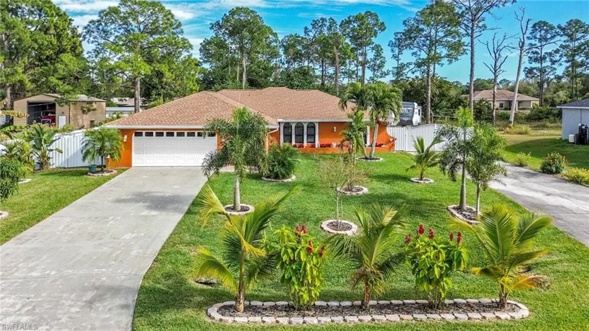 View of front facade featuring concrete driveway, an attached garage, view of scattered trees, and roof with shingles