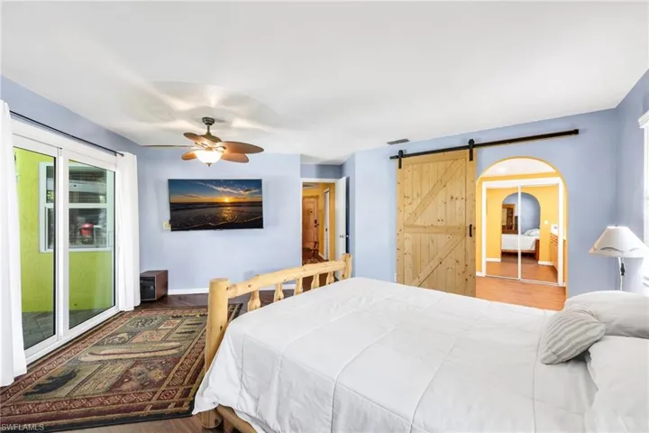 Bedroom featuring a barn door, wood finished floors, ceiling fan, and a closet