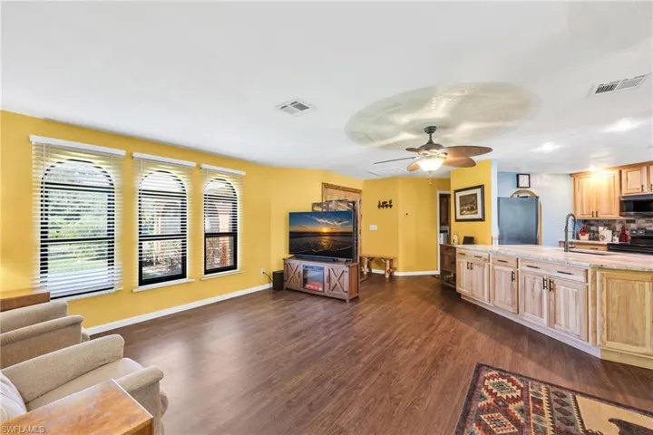 Living room with ceiling fan and dark wood-style flooring