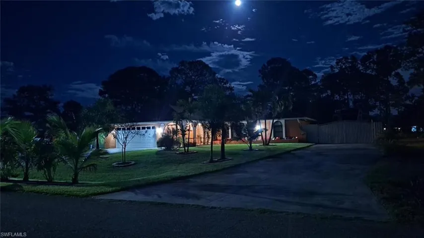 View of front facade with a yard, driveway, and a gate