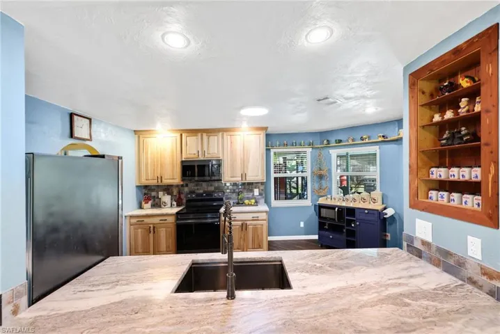 Kitchen with black appliances, tasteful backsplash, open shelves, a textured ceiling, and light stone counters
