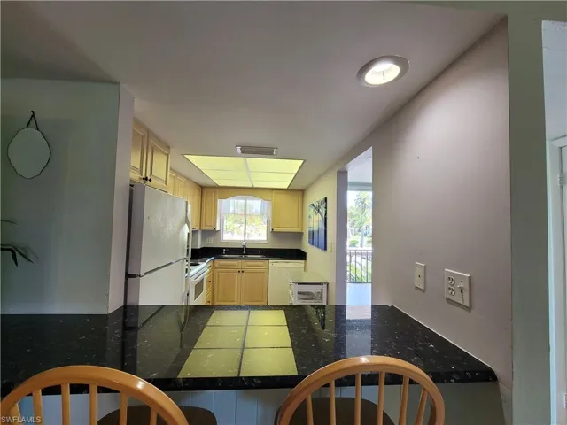 Kitchen featuring sink, white appliances, and kitchen peninsula